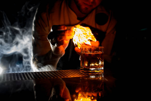 istock Professional bartender serving the transparent alcoholic cocktail with ice fire sprinkling with the lemon juice 1201713168