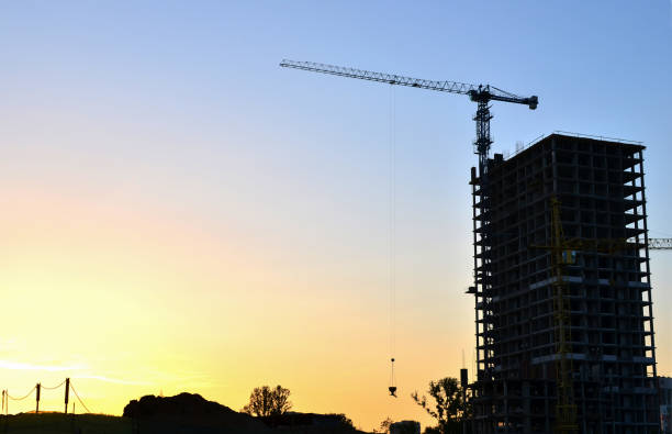 istock Tower crane constructing a new residential building at a construction site at sunset background. Renovation program, development, concept of the formworks industry. Selective focus. Place for text. 1201713244