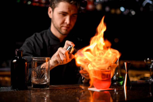istock Male bartender serving the red alcoholic cocktail with ice under the fire 1201713388