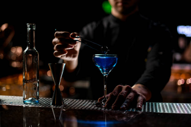 istock Bartender throwing to the blue alcoholic drink one berry with tweezers 1201713879