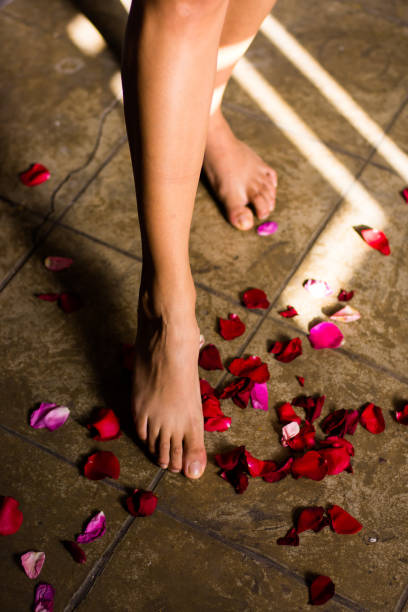 istock woman's bare feet walking on some rose petals in romantic atmosphere 1201714924