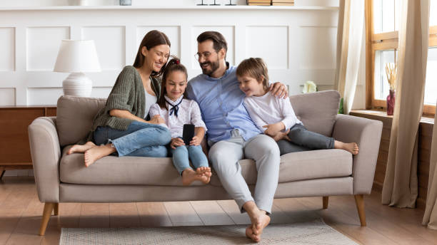 istock Happy family with kids relax on couch using cell 1201716232
