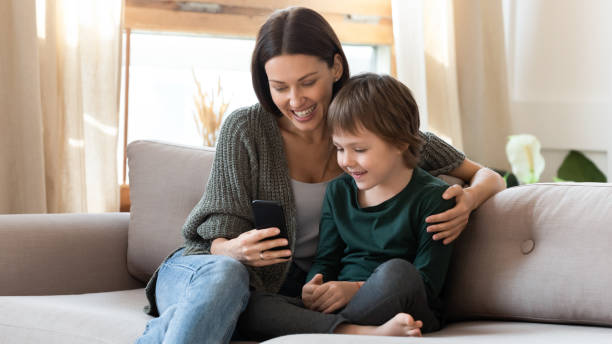 istock Caring mum relax on couch using cell with little son 1201716262
