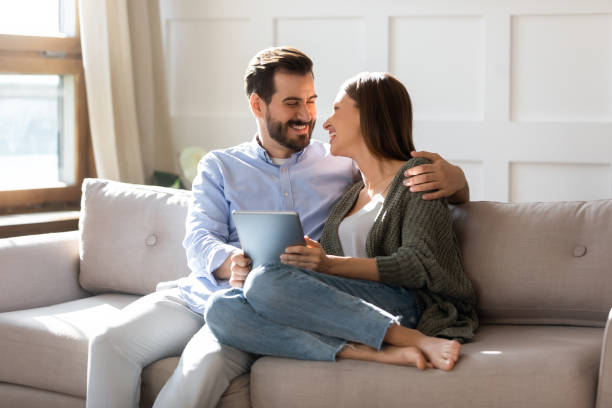 istock Millennial couple sit on couch surfing web on tablet 1201716266