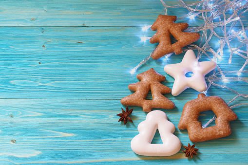 Gingerbread in the shape of a star, Christmas tree and house, star anise and garland on a blue wooden background
