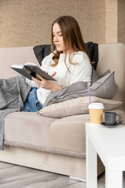 istock young lovely girl resting with a book while lying on a sofa 1201726331
