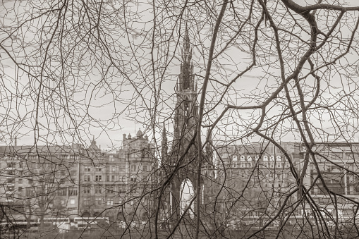Detail of bare branches of a tree in winter against the backdrop of the Scott Monument and Princes Street in Edinburgh, Scotland.  The Scott Monument celebrates the life of Sir Walter Scott.  It was constructed in 1846 to a design of George Kemp.  Selective focus.