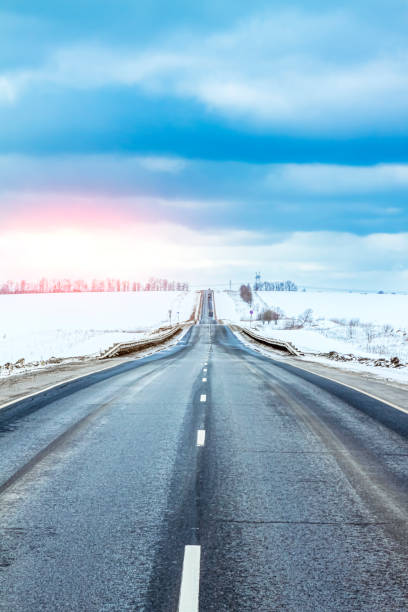 istock Winter road going over the horizon. Blue clouds above the road. 1201727742