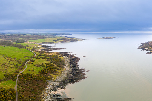A high angle view of a Scottish coastal scene with small island, and the Solway Firth in the background. The image was captured by a drone on on an overcast winter morning as the tide was going out.