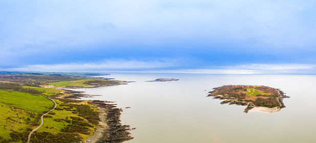 A high angle view of a small Scottish island with Wigtown Bay and the Solway Firth in the background. The image was captured by a drone on on an overcast winter morning as the tide was going out.