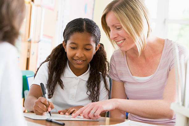 istock Schoolgirl sitting with her teacher in class 120172924