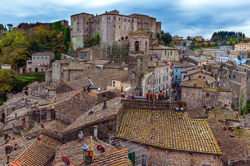 Italy. The tufa city of Sorano. Tiled roofs of houses, narrow streets amidst gloomy walls and stone steps. The concept of active, historical and photo tourism