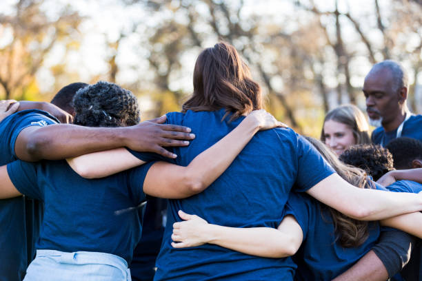 istock Standing with arms around each other, volunteers get pep talk 1201729965