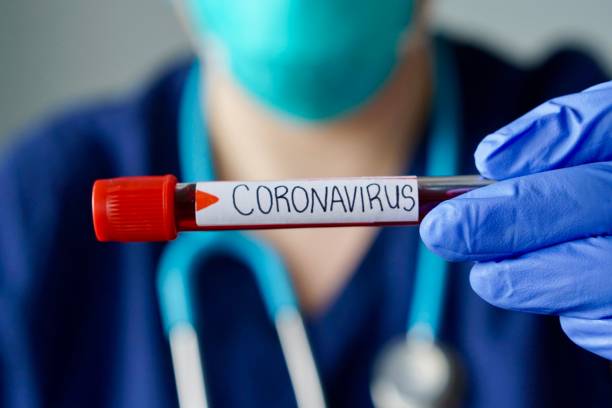 Nurse wearing respirator mask holding a positive blood test result for the new rapidly spreading Coronavirus, originating in Wuhan, China stock photo