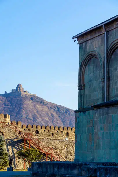Tbilisi, winter. The Jvari monastery stands on a mountain in the background. In the foreground, the battlements of the monastery wall and the wall of the temple. Winter cold picture