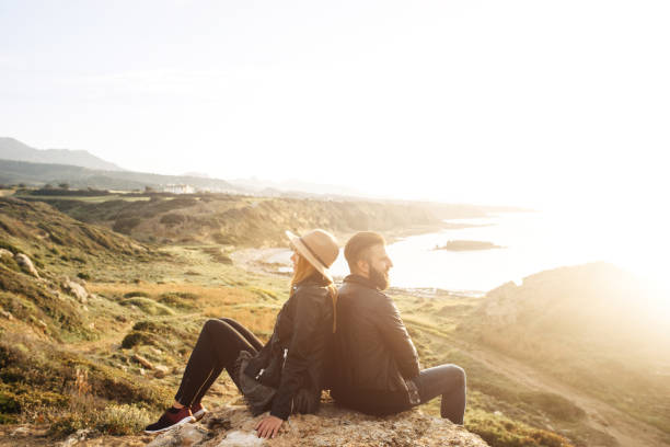 istock young couple sitting on a rock back to back 1201750896