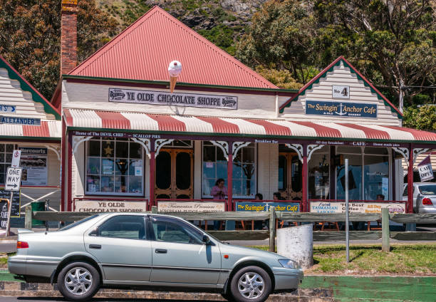 Stanley, Tasmania, Australia - December 15, 2009: Church street with Ye Olde Chocolate Shoppe and the Swingin Anchor Cafe. Car up front, people on patio, and green foliage in back.