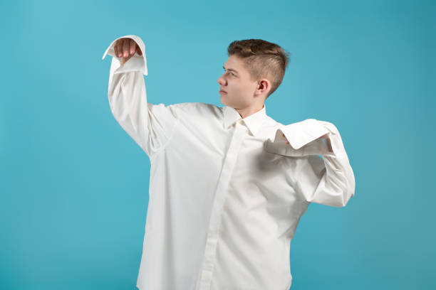 ein junger mann in einem übergroßen weißen hemd zeigt, dass sein hemd zu groß für ihn ist - übergröße stock-fotos und bilder