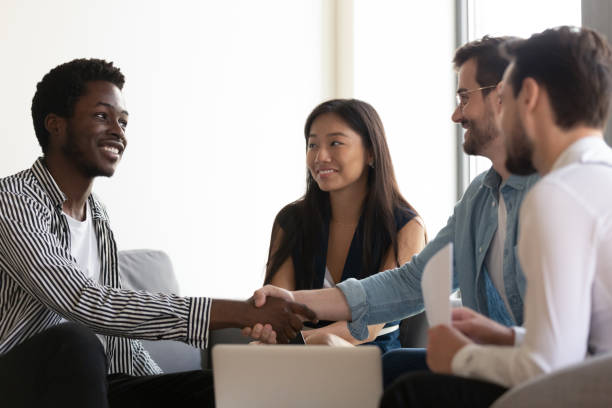 istock Multiethnic partners sitting on couch shake hands start group meeting 1201756548