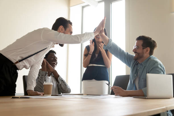 hombres emocionados líderes del equipo dando cinco altos compartiendo éxito común - agreement businesswoman togetherness opportunity fotografías e imágenes de stock