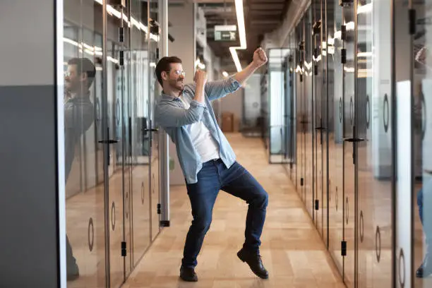 Photo of In office hallway dancing worker got promotion celebrating business success