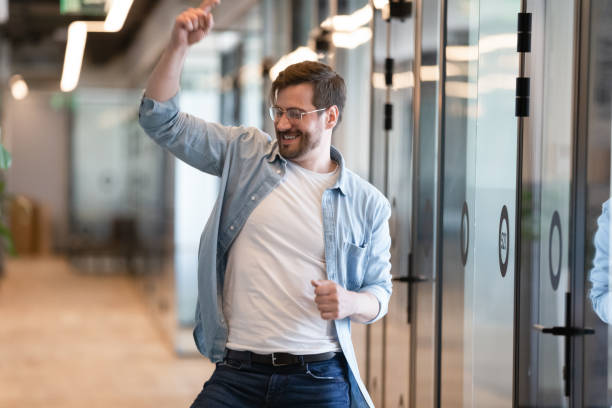 istock Funny male worker dancing in modern office hallway feels overjoyed 1201756591