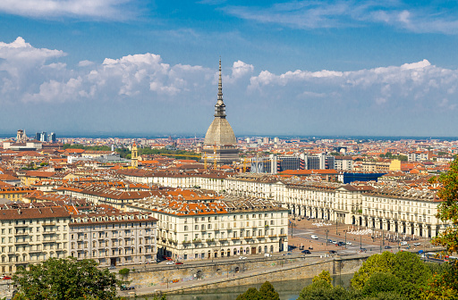 Aerial top panoramic view of Turin city center skyline with Piazza Vittorio Veneto square, Po river and Mole Antonelliana building with high spire, blue sky white clouds background, Piedmont, Italy