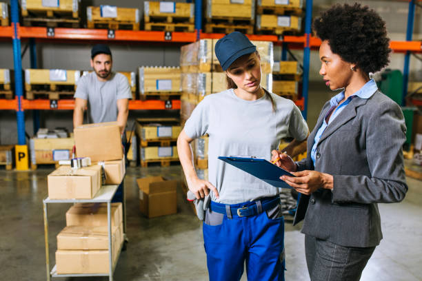 istock Female supervisor evaluate work in storage room and writing at notepad 1201756968