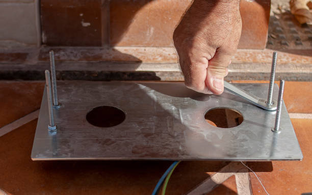 istock Engine installer placing a metal anchor plate to the ground using screws and nuts, which is carefully tightened with a wrench 1201765629