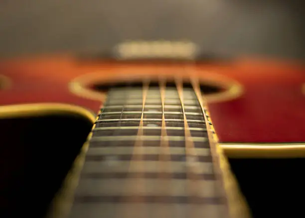 Photo of Fretboard of an acoustic sunburst guitar