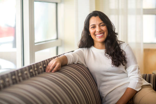 istock Hispanic woman sitting on the sofa smiling. 1201767899