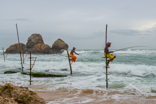 Koggala - Sri Lanka : 09-August-2019 : The fishermen sit on a cross bar and waits until a fish comes along to be caught.