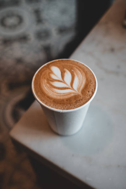 Take away coffee with latte art on white marble table.