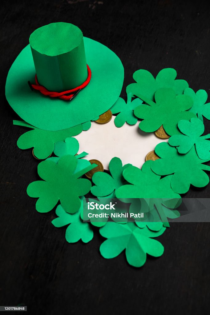 Happy St Patricks Day green leprechaun hat with gold covered chocolate coins on dark wood background, with applied retro style faded filters. Archival Stock Photo