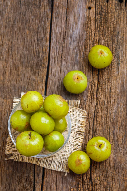 Fresh Indian gooseberry in glass bowl on wooden background stock photo