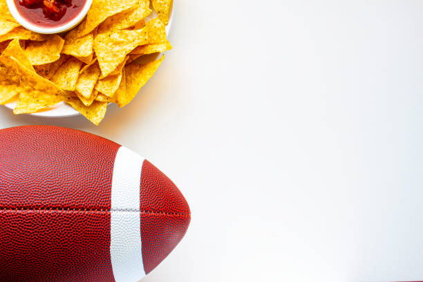 an american football with organic nacho chips and mild salsa on the side on a white background - lanche da tarde imagens e fotografias de stock