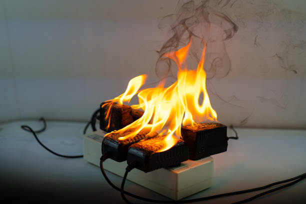 On fire adapter charger at plug Receptacle on black background, Electric short circuit failure resulting in electricity wire burnt