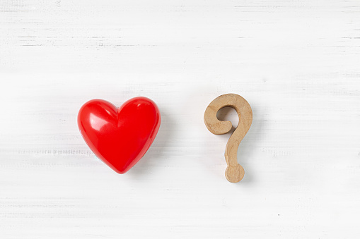 Question Mark and Red Heart on white wood background. Solving Problem of Love Concept.