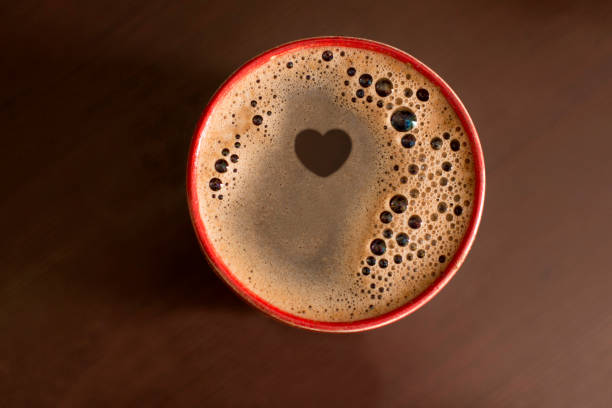 Paper cup of coffee latte and coffee beans on wooden table