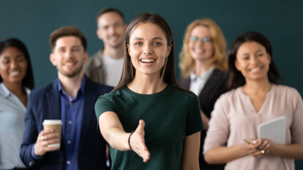 il rappresentante dell'azienda donna tiene la mano per il cliente che accoglie la stretta di mano - gruppo medio di persone foto e immagini stock