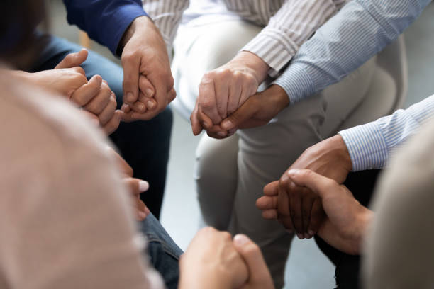 People sitting in circle holding hands at group therapy session Close up people sit in circle holding hands participating at group therapy session. Receiving sharing psychological support, go through addiction together, help each other overcome dependence concept alcoholics anonymous photos stock pictures, royalty-free photos & images