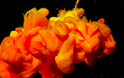 Fiery abstract stylish modern background. Yellow m orange watercolor ink in water. Powerful explosion of colors on a black background. Cool trending screensaver.