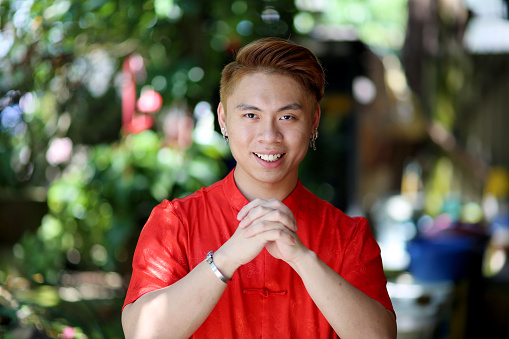 A young man is feeling cheerful with greetings hand gesture during Chinese New Year celebration in Johor, Malaysia.