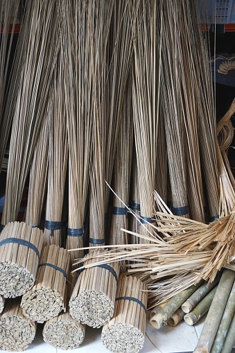 Bundles of split bamboo splints, handcrafted brooms and natural fibers for sale at a market stall in Bali Indonesia