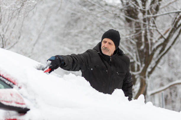 istock Man removing snow with ice scraper from a car 1201806377