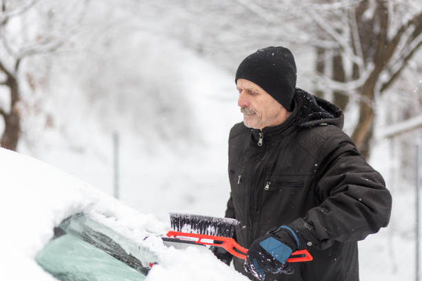 istock Older man holding ice  scraper with a brush on the other side 1201806384