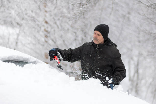 istock Elderly man sweeping snow from car 1201806390