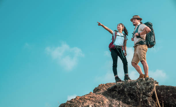 молодая азиатская пара туристов поднимается на вершину горы. два человека туристов на вершине горы наслаждаясь видом на долину. туристы с р - rock human hand human arm climbing стоковые фото и изображения
