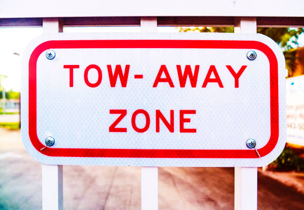 Metal Red and White Tow Away Sign on a White Metal Fence at the ENtrance of a Building. Tow-Away Zone Metal Sign in Red and White.