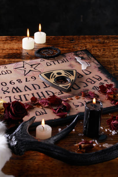 istock Talking board and planchette, also known as Ouija board, used for communicating with the dead and other spirits. The atmosphere of black art with candles and horns of the animal. 1201809689
